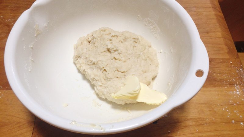 子供と作る手作りパン生地にバターを入れ揉みこみます。